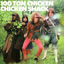 Text oben: "100 TON CHICKEN CHICKEN SHACK". Vier Personen in Kostümen stehen in einer grünen, bewaldeten Umgebung.