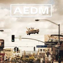 Text: "AEDM" und "Reunion Rd EST. 2003." Ein Auto fliegt über eine belebte Stadt mit Ampeln und Schildern.