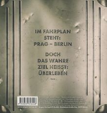 Prägung mit Text: "IM FAHRPLAN STEHT: PRAG – BERLIN DOCH DAS WAHRE ZIEL HEISST: ÜBERLEBEN." Metallisch geprägter Hintergrund.