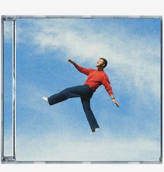 Kein sichtbarer Text. Ein Mann in rotem Pullover und blauer Hose schwebt im blauen Himmel.