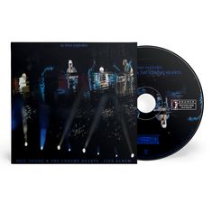 CD und Cover mit dem Text: "as time explodes" und "NEIL YOUNG & THE CHROME HEARTS LIVE ALBUM". Verschwommene Bühnenlichter im Hintergrund.
