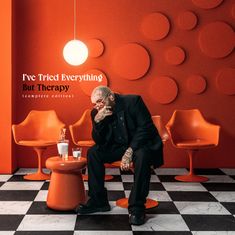 Texte: "I've Tried Everything But Therapy (complete edition)". Ein nachdenklicher Mann sitzt in einem orange eingerichteten Raum.