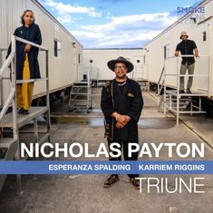 NICHOLAS PAYTON, ESPERANZA SPALDING, KARRIEM RIGGINS, TRIUNE. Drei Personen vor weißem Gebäudekomplex.