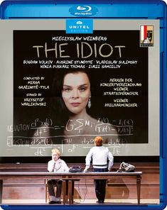 "THE IDIOT" von Mieczysław Weinberg. Personen vor einer Wand mit mathematischen Formeln, eine Frau wird abgebildet.