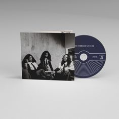 Text auf CD: "THE WOMACK SISTERS". Schwarze CD neben einem schwarz-weißen Foto von drei elegant gekleideten Frauen.