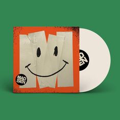 Text: "MADSEN" auf schwarzem Kreis. Klebeband in M-Form mit aufgemaltem Smiley auf orangefarbenem Hintergrund. Vinyl daneben.