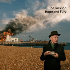 Text: „Joe Jackson Hope and Fury.“ Eine Illustration zeigt einen Pier in Flammen, daneben steht ein Mann mit einer Tasse Tee.