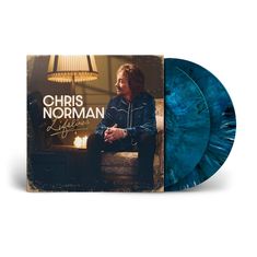 „Chris Norman Lifelines“ in weißer Schrift. Ein Mann sitzt auf einem Sofa, daneben sind zwei blau-gemusterte Schallplatten.