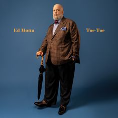 „Ed Motta“ links, „Toe-Toc“ rechts in orange. Mann im Anzug hält Regenschirm vor blauem Hintergrund.