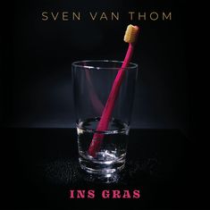 "Sven van Thom" oben, "Ins Gras" unten. Glas mit einer roten Zahnbürste darin vor schwarzem Hintergrund.