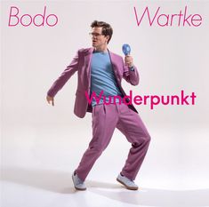 „Bodo Wartke Wunderpunkt“. Ein Mann in rosa Anzug posiert mit blauem Fächer, lässig und schwungvoll.