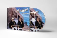 „Amigos - Cleopatra“ steht in goldener Schrift. Zwei Männer sitzen vor einem ägyptischen Gebäude. Sie tragen schwarze Hemden.
