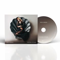 "FREYA RIDINGS MOTHER OF PEARL" steht unten. Eine Frau in schwarzem Kleid ruht in einer großen Muschelschale.