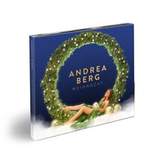 Text: "Andrea Berg Weihnacht". Frau in grünem Kleid liegt bei einem weihnachtlichen Kranz aus Tannenzweigen und Kugeln.