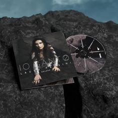 "IO CANTO, Laura Pausini, Deluxe." Albumcover neben einer CD auf dunklem, steinigen Hintergrund.