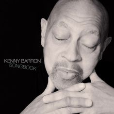 Aufschrift: "KENNY BARRON SONGBOOK." Ein Mann mit geschlossen Augen, seine Hände unter dem Kinn verschränkt.