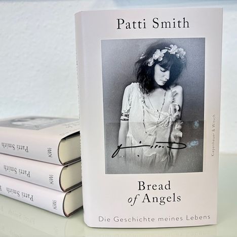 Auf dem Buchcover steht: "Patti Smith, Bread of Angels, Die Geschichte meines Lebens". Schwarz-weiß Foto einer Frau mit Blumenkranz.