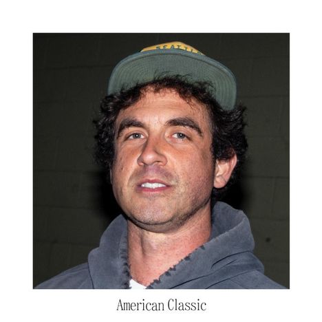 Text: "American Classic". Ein Mann mit lockigem Haar trägt einen Kapuzenpullover und eine Cap.