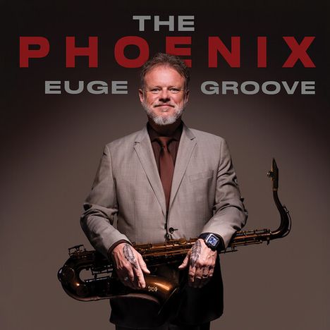 Die Worte "THE PHOENIX, EUGE GROOVE" sind groß geschrieben. Ein Mann im Anzug hält ein Saxophon und lächelt.