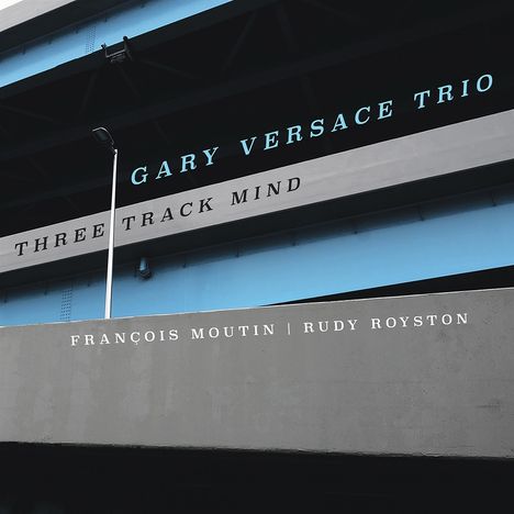 Der Text sagt: "GARY VERSACE TRIO, THREE TRACK MIND, FRANÇOIS MOUTIN | RUDY ROYSTON" auf Brückenstruktur.