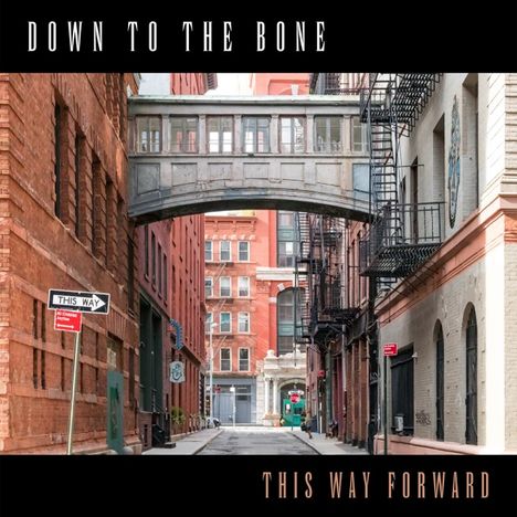 Texte: "Down to the Bone", "This Way Forward", "This Way". Städtische Gasse mit Brücke zwischen roten Backsteingebäuden.