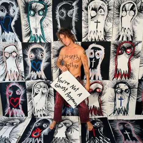 Texte: "Joseph Arthur", "You're Not A Ghost Anymore". Eine Person steht vor Zeichnungen mit gespenstischen Gesichtern.