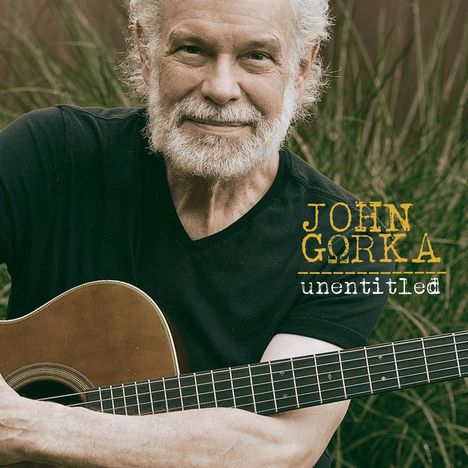 Text: "JOHN GORKA unentitled." Ein Mann mit weißem Haar und Bart hält eine Gitarre, im Hintergrund sind Gräser.