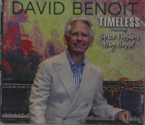 Der Text sagt: "DAVID BENOIT TIMELESS Featuring Spice Fusion Big Band". Ein Mann im Anzug lächelt vor einem bunten Hintergrund.