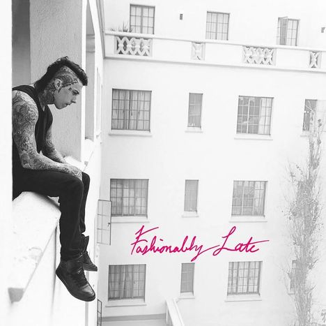 "Fashionably Late" in pink. Ein tätowierter Mann sitzt gedankenverloren auf einer Balkonbrüstung eines hellen Gebäudes.
