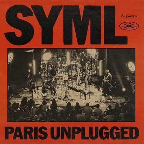 Text "SYML PARIS UNPLUGGED". Live-Konzertszene mit Musikern auf einer Bühne, umgeben von Publikum und Beleuchtung.