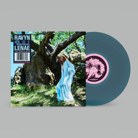 „RAVYN LENAÈ, Blue Island, THE THIRD ALBUM.“ Frau in hellblauem Kleid vor einem Baum, Vinyl daneben.