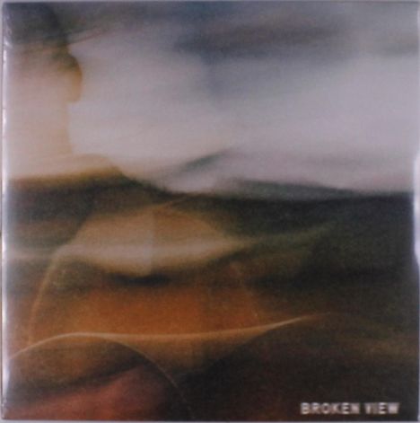 Text: "BROKEN VIEW." 
Das Bild zeigt abstrakte, verschwommene Farbtöne in Erdtönen und Blau.