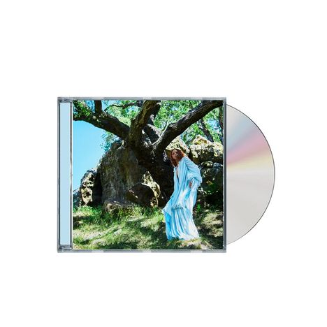 CD-Hülle mit einem Foto. Eine Person in hellblauem Gewand steht neben einem großen Baum im Sonnenlicht.
