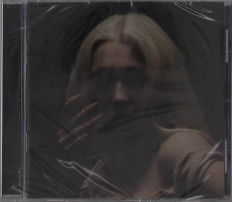 Ich sehe keinen Text. Eine verschwommene Frau mit blonden Haaren, die Hand vor dem Gesicht.