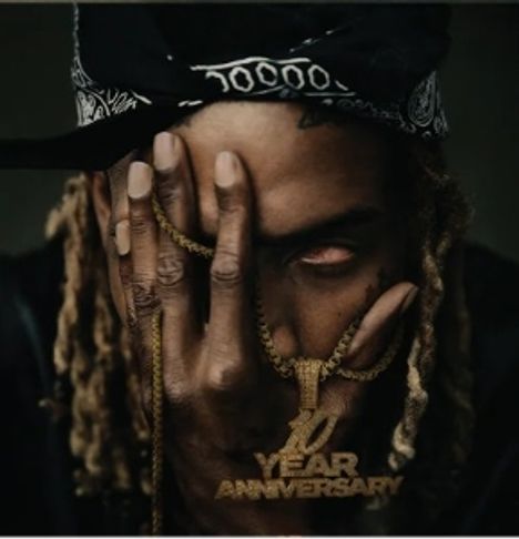 „10 YEAR ANNIVERSARY“, Mann bedeckt Gesicht mit Hand, trägt Kette und Bandana.