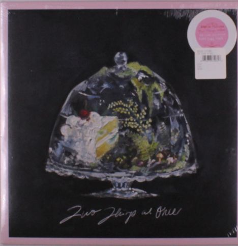 "Two Things at Once" auf schwarzem Hintergrund, darunter eine Glasglocke mit Blumen und einem Kuchenstück.