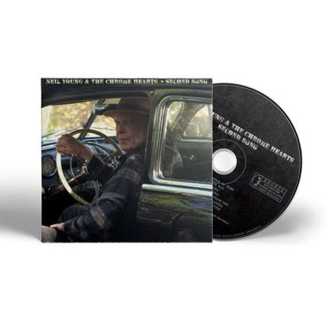 "Neil Young & The CHROME HEARTS - SECOND SONG." Ein Mann sitzt am Steuer in einem Auto, daneben eine CD.