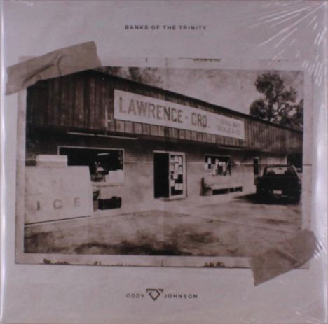Oben steht "BANKS OF THE TRINITY". Ein Gebäude mit dem Schild "LAWRENCE - GRO." Ein Pickup steht daneben.