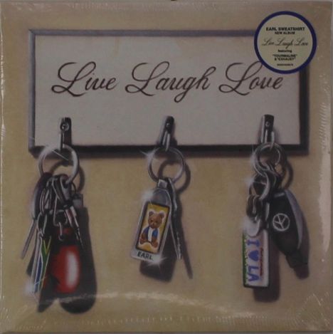 "Live Laugh Love" auf einem Schild, darunter drei Schlüsselbunde mit Anhängern, darunter ein Bär mit "Earl".