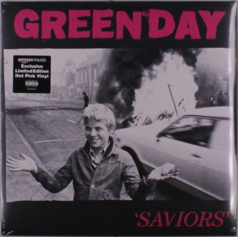 „GREENDAY“ und „SAVIORS“ in großer Schrift. Ein Junge steht lächelnd mit erhobenen Händen vor einem brennenden Auto.