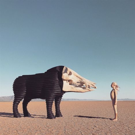 © Hinweis. 

Ein Kind steht vor einer Skulptur in Form eines Tieres mit einem Schädel, umgeben von einer weitläufigen Wüstenlandschaft.