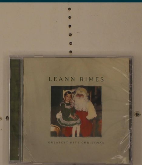 CD-Cover mit Text "LEANN RIMES" und "GREATEST HITS CHRISTMAS". Bild: Kind in grünem Kleid mit Weihnachtsmann.