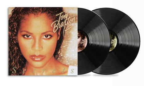 "Secrets", "Toni Braxton" in eleganter Schrift. Zwei schwarze Schallplatten. Porträt einer Frau mit intensivem Blick.