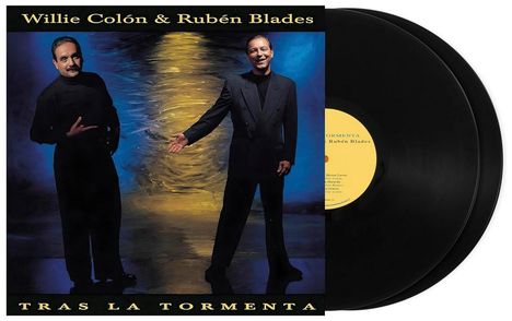 "Willie Colón & Rubén Blades", "TRAS LA TORMENTA". Zwei lächelnde Männer in Anzügen vor einem abstrakten Hintergrund.