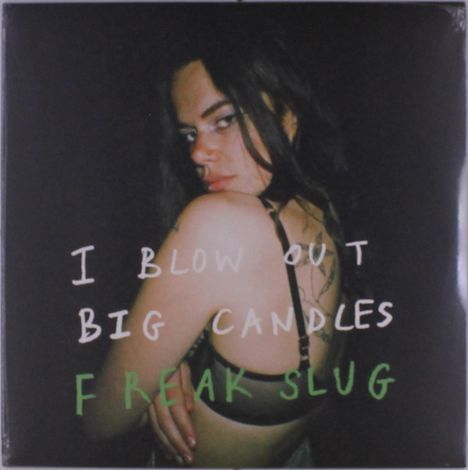 Text: “I Blow Out Big Candles Freak Slug”. Eine Frau schaut über ihre Schulter, trägt ein schwarzes Top und hat langes Haar.
