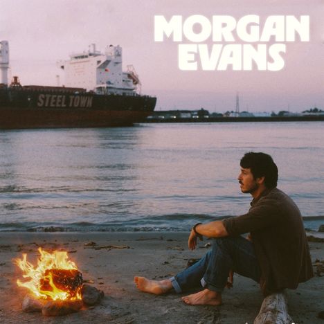 "Morgan Evans" und "STEEL TOWN" sind Texte. Ein Mann sitzt nachdenklich am Strand vor einem Feuer, im Hintergrund ein Frachtschiff.