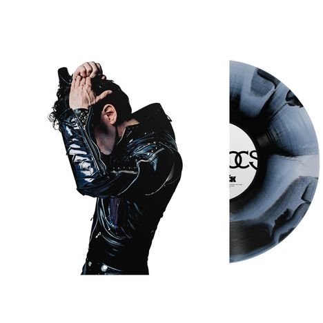Rechts ein Vinyl mit schwarzer und grauer Marmorierung, links eine Person in schwarzer Lederjacke mit erhobenen Armen.
