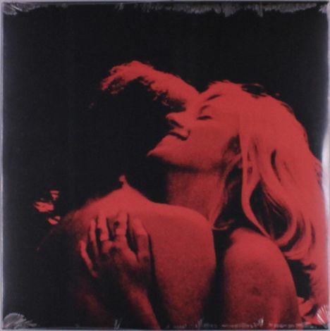 Zwei Personen umarmen sich, ihre Haut und Haare sind in einem kräftigen Rotton gefärbt, während der Hintergrund schwarz ist.