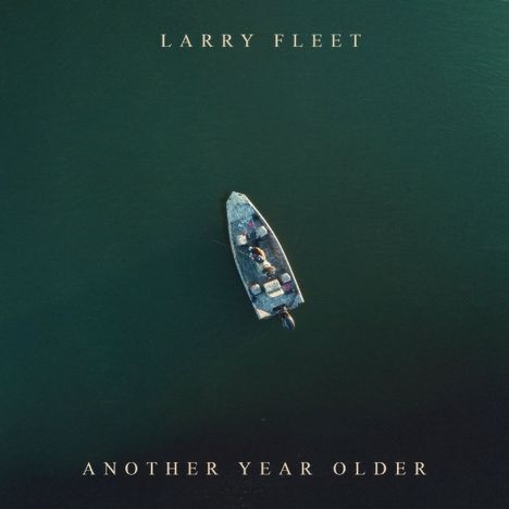 "LARRY FLEET, ANOTHER YEAR OLDER" über einem Boot in der Mitte eines grünen Gewässers von oben.