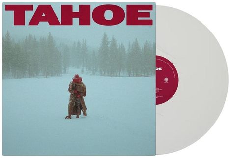 Text: TAHOE. Ein vermummter Mensch steht alleine auf einem schneebedeckten Feld, umgeben von Bäumen.